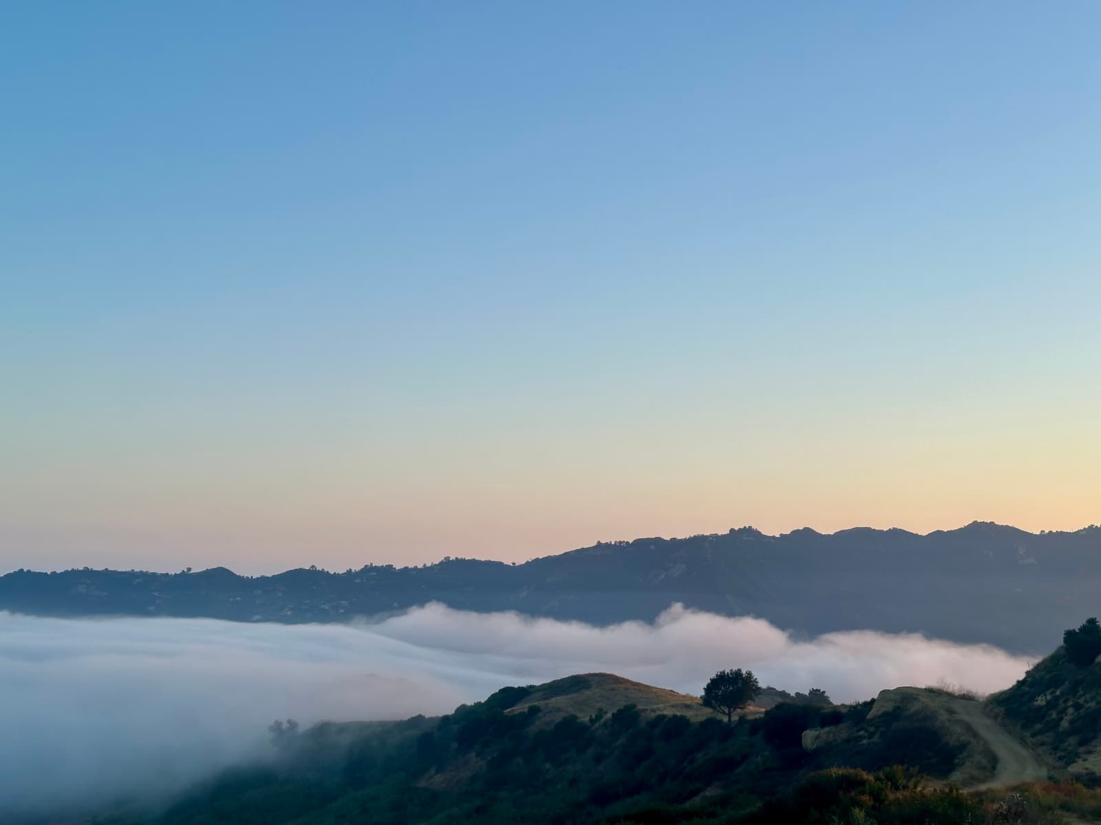 A ridgeline at golden hour with fog moving through the valley below, in the founder's own photograph.